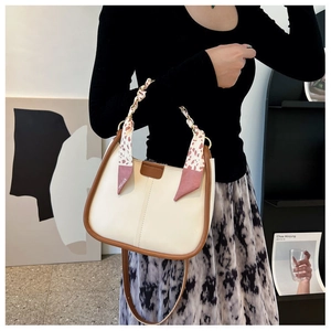 Detail of cream-white bucket bag with brown trim and floral silk scarf on the handle