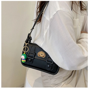 Detail of black crossbody bag with dog embroidery and green dinosaur doll charm