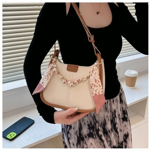 Detail of cream shoulder bag featuring pink leopard silk scarf and gold chain accent