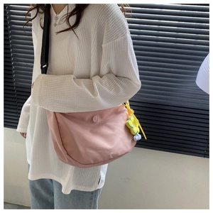 Pink dumpling crossbody bag featuring a yellow flower charm and adjustable black strap