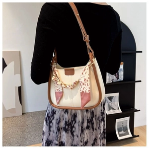 Detail view of stylish cream shoulder bag with brown leather trim and floral silk scarf