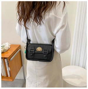 Detail of a black crossbody bag featuring a cute cartoon dog embroidery on the flap