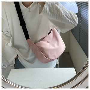 Close-up of pink crescent nylon crossbody bag with adjustable wide black strap