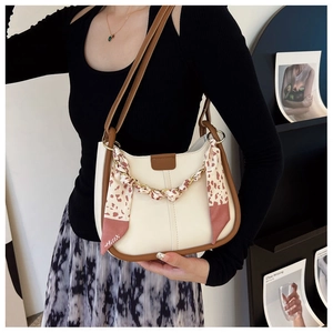 Detail of cream leather bucket bag with leopard print silk scarf handle and gold chain