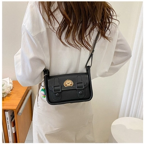 Detail of black leather crossbody bag with cartoon dog patch and green quirky charm