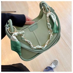Detail of green hobo bag with floral scarf wrapped gold chain handle in hand