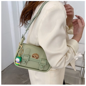 Close-up of a light green leather shoulder bag featuring a cute puppy patch and charm