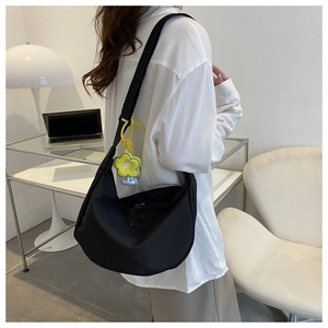 Detail of black nylon crescent crossbody bag with sunflower charm shown on a model