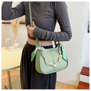 Detail of light green saddle bag with floral silk scarf handle and gold chain decoration
