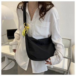Close-up of black nylon crescent crossbody bag featuring a bright yellow flower charm