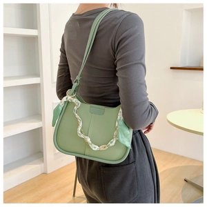 Detail of light green bucket bag with floral scarf and gold chain on model's shoulder