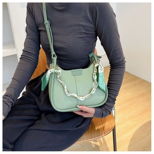 Light green leather bucket bag with silk scarf chain strap worn by a model
