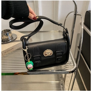 Detail of black square shoulder bag with cartoon dog patch and green monster charm