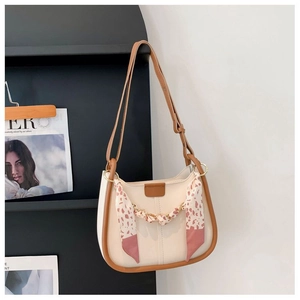 Detail of cream leather baguette bag with brown piping and silk scarf chain decoration