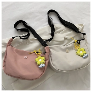 Detail of crossbody crescent bags in pink and beige with sunflower pendants