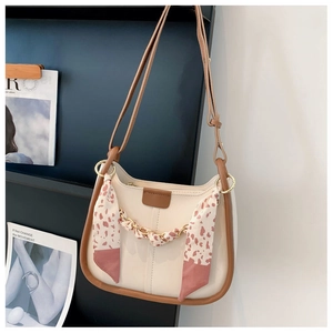 Detail of beige underarm bag with floral scarf, gold chain and brown piping accents