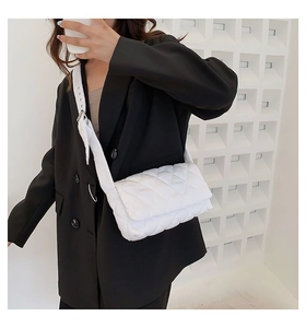 Gros plan sur un sac bandoulière blanc matelassé avec rabat sur un blazer noir