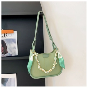 Detail of light green bucket bag featuring a silk scarf wrapped chain and metal strap