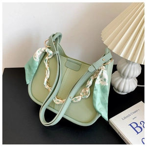 Detail of light green crescent bag with silk scarf handle and gold chain decoration
