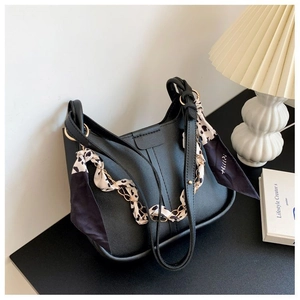 Detail of black lychee grain leather handbag with leopard print scarf and chain