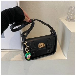 Detail of black crossbody bag with cute animal embroidery and dinosaur doll pendant