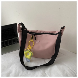 Close-up of pink nylon crossbody bag with black strap and yellow sunflower charm detail