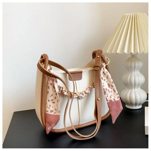 Detail of stylish bucket bag with floral scarf decor on a dark minimalist surface