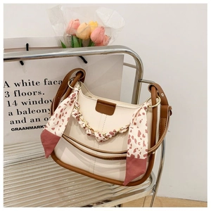 Detail of a chic cream and brown leather shoulder bag with a floral silk scarf handle
