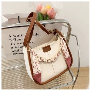 Detail of a beige and brown PU bucket bag with floral scarf and metal chain handles