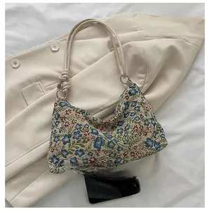 Detail of vintage floral jacquard shoulder bag with tied straps on beige blazer