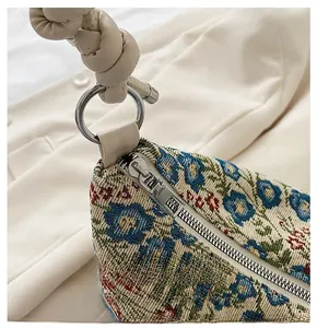 Detail of floral jacquard fabric bag with silver zipper and twisted rope handle