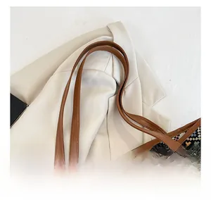 Detailed close-up of wide brown leather straps and colorful woven canvas tote bag
