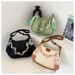 Close-up of stylish bucket bags with decorative silk scarves and metal chain straps