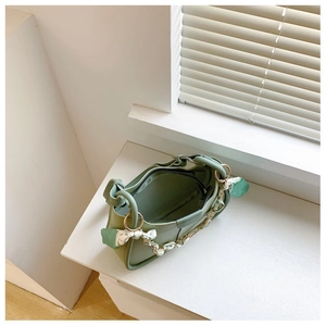 Detail view of light green leather bucket bag with floral scarf handle and zipper opening