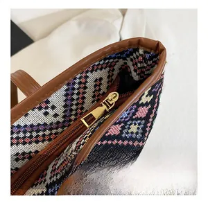 Detailed close-up of colorful woven fabric tote bag with smooth metal zipper and leather strap