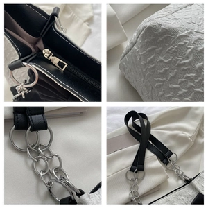 Détail du sac cabas plissé blanc avec chaînes à anneaux argentés et texture de la poignée