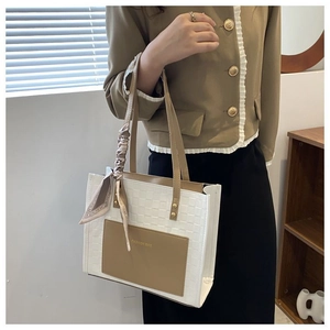 Détail du sac cabas tissé avec poche kaki et poignée décorative en foulard de soie imprimé