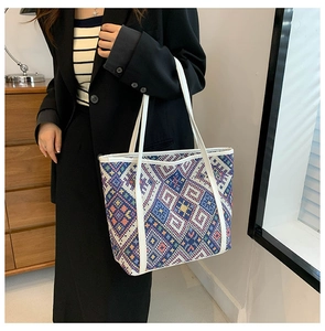 Detail of colorful geometric woven canvas tote bag with white leather handle trim
