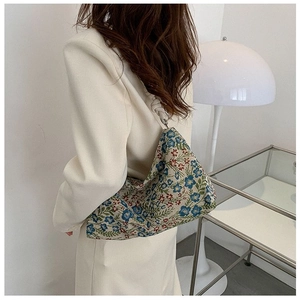 Detail of vintage floral jacquard shoulder bag with decorative knotted strap on a model