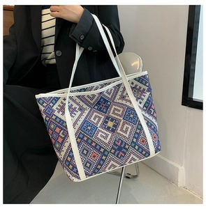 Detail of bohemian canvas tote bag showing colorful geometric woven texture and white strap