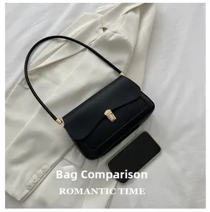 Detail view of the black saddle bag with gold buckle next to a phone for size reference