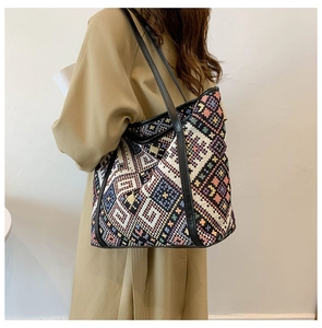 Detail of woven tote bag with colorful ethnic patterns and black leather straps