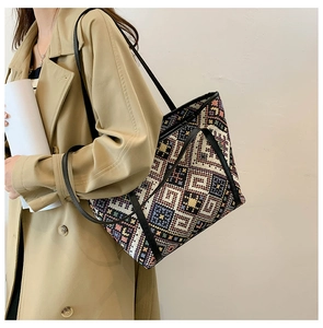 Detailed close-up of colorful geometric woven tote bag with premium black leather straps