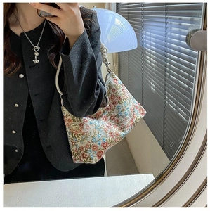 Detailed close-up of floral jacquard canvas hobo bag with sleek leather shoulder strap