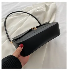 Close-up of minimalist black matte leather saddle bag with elegant gold metal buckle