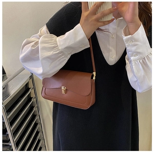 Detail of caramel vintage saddle bag featuring elegant gold metal clasp and smooth leather texture
