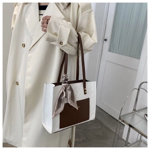Détail du sac cabas bicolore avec texture gaufrée et foulard en soie sur la poignée