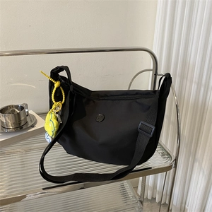 Minimalist black nylon crescent crossbody bag with yellow flower charm and wide strap