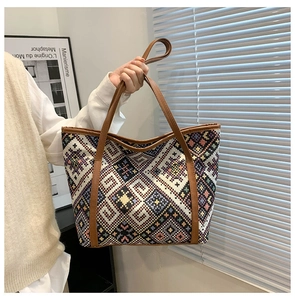 Close-up of geometric woven pattern and brown leather handles on a large canvas tote bag