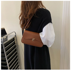 Close-up of brown leather saddle bag featuring a classic gold metal buckle and flap